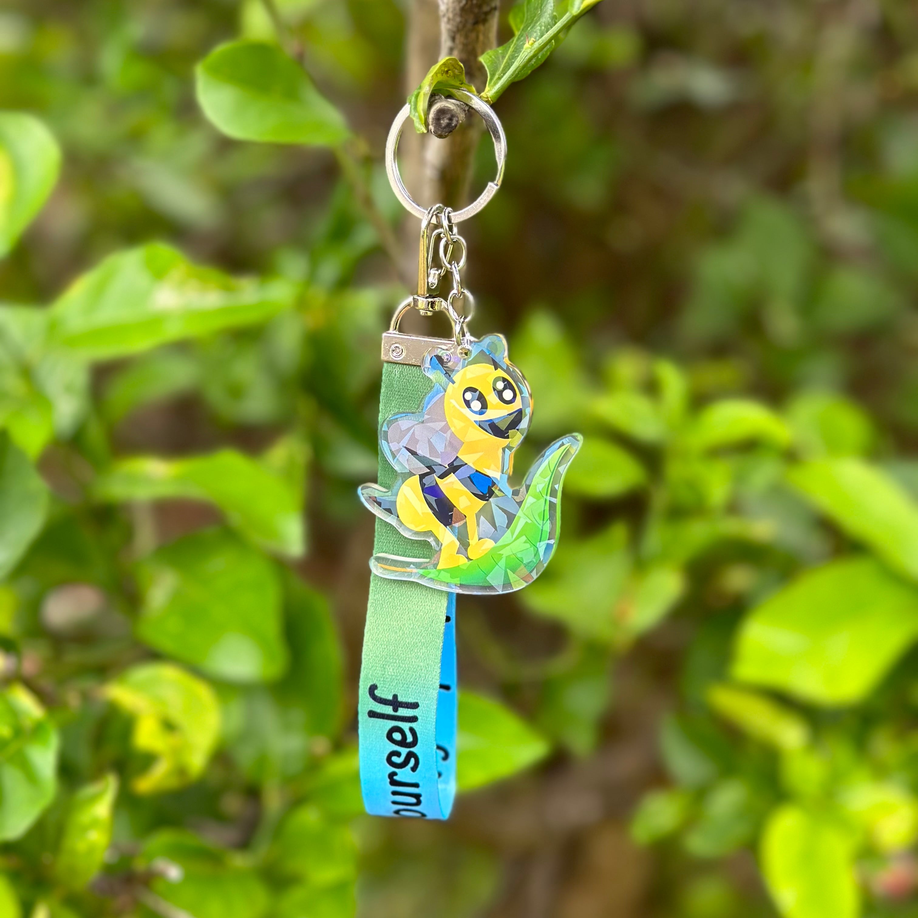 A bee riding a leaf holographic acrylic keychain, with a lanyard that says "bee leaf in yourself"