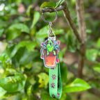Cattle Dog Flash Acrylic Holographic Keychain, with a green lanyard with brown paws on it hanging off a tree