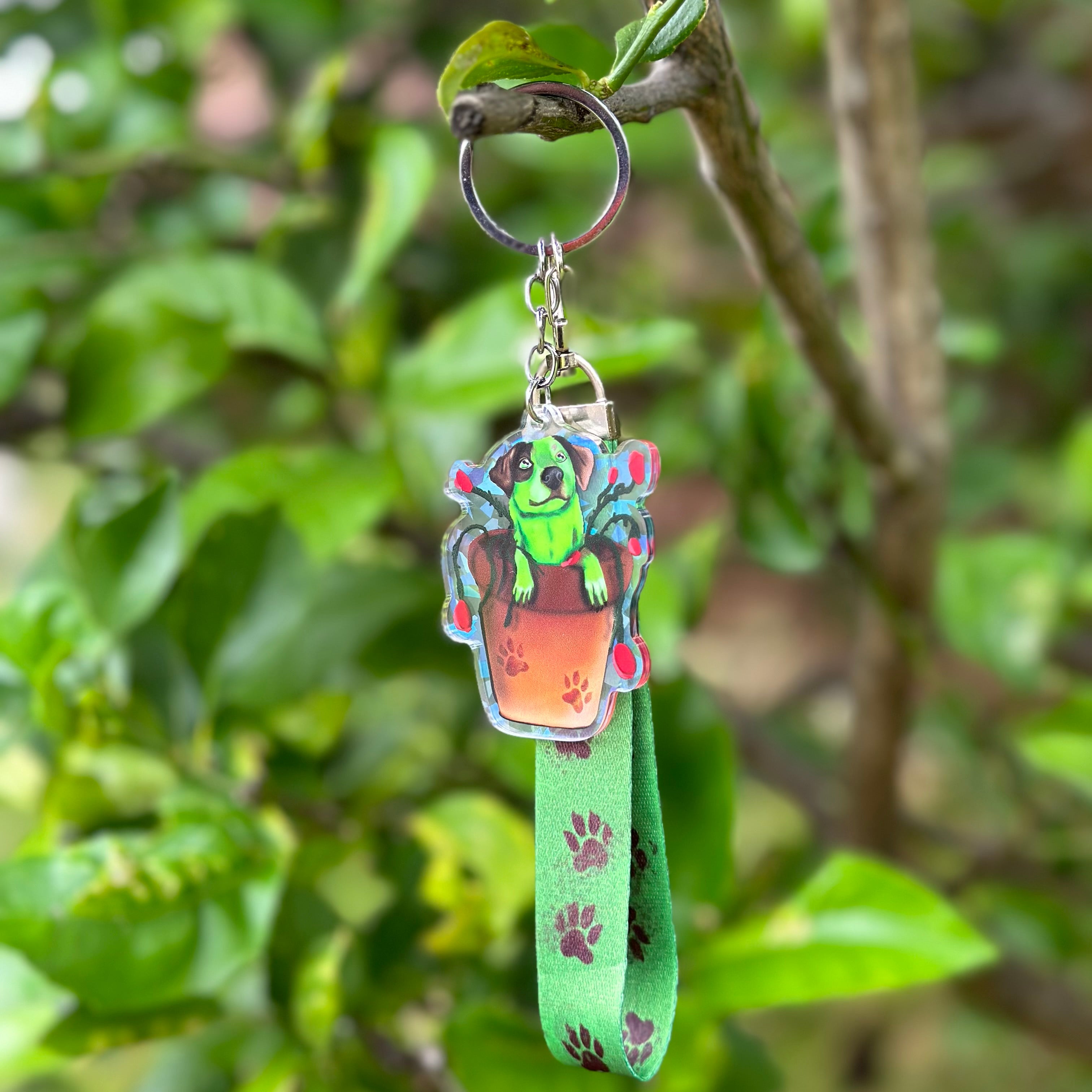 Cattle Dog Flash Acrylic Holographic Keychain, with a green lanyard with brown paws on it hanging off a tree