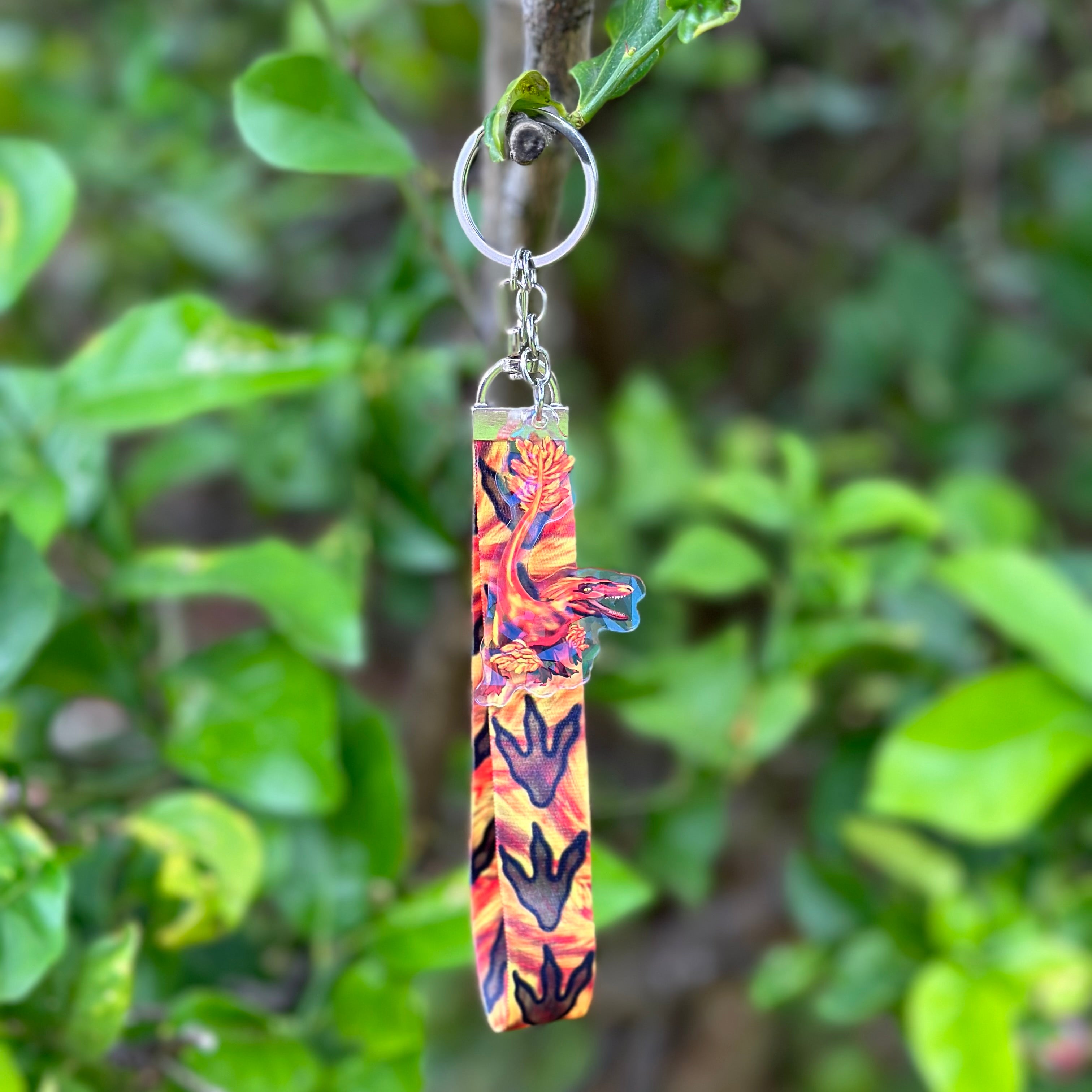 Red fiery Pyroraptor Dinosaur Acrylic Holographic Keychain with a fiery lanyard that has dinosaur paws Lanyard